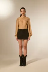 Minifalda negra de poliéster con corte al cuerpo, tiro alto y detalle de tachas doradas decorativas a lo largo de la costura lateral y el bolsillo delantero.