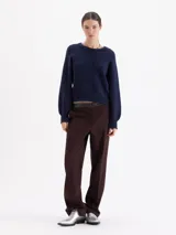 Pantalón de corte recto confeccionado en tela sastrera, con cintura de cuero vacuno, raya marcada en el centro de las piernas y bolsillos laterales.