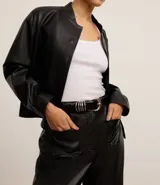 Cinturón negro de cuero sintético con hebilla redonda dorada y detalle de argollas plateadas.