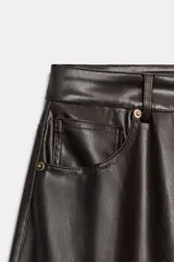 Pantalón de tiro medio con diseño tipo ballon, confeccionado en material con efecto piel. Cuenta con cinco bolsillos, cierre frontal con cremallera y botón metálico.