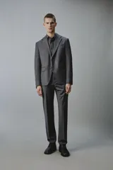 Blazer gris oscuro de corte regular fit con diseño de raya diplomática, confeccionado con mezcla de lana. Presenta solapas de muesca, cierre frontal de dos botones, bolsillos con solapa en la cadera y un bolsillo de vivo en el pecho.