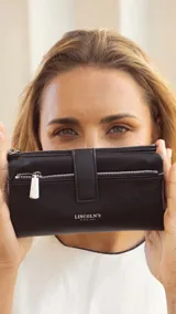 Billetera Lincoln's de mujer en color negro, confeccionada en símil cuero con textura granulada. Presenta un diseño rectangular con cierre de broche, bolsillo frontal con cierre metálico, correa de mano extraíble y logo de la marca grabado en el frente.