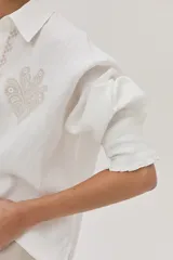 Camisa blanca de lino con bordados beige en la cartera y el bolsillo.