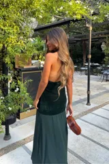 Vestido largo verde oscuro de terciopelo y satén, con escote halter pronunciado y diseño ajustado en el torso con caída fluida en la falda.