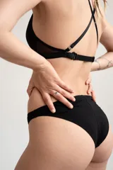 Bombacha de tiro medio-alto color negro, con diseño clásico confeccionado en algodón y elastano, con tiras finas elásticas en los laterales.