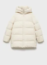 Campera acolchada tipo puffer de color beige, con diseño recto, cuello alto y capucha integrada. Presenta cierre frontal de cremallera doble y bolsillos laterales con cierre.