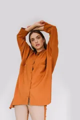 Camisa de sarga color mostaza, de diseño irregular con los costados más largos, mangas largas y corte amplio.