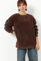 Buzo negro de tela tipo teddy, de manga larga y cuello redondo. Presenta recortes de nylon en mangas y laterales.