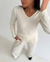 Remera de lanilla color crema con textura acanalada, escote en V y mangas largas. Presenta un diseño ajustado al cuerpo.