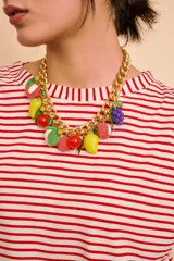 Collar de cadena gruesa dorada con dijes colgantes en forma de frutas coloridas, hojas verdes y cuentas de cristal.
