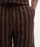 Bermuda masculina confeccionada en tejido jacquard con estampado de rayas texturizadas en color marrón. Posee cintura elástica con cordón ajustable y bolsillos laterales.