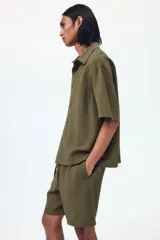 Pantalón corto de tejido texturizado verde militar, con corte relajado, cintura elástica con cordón de ajuste y bolsillos laterales.