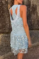 Vestido corto celeste de encaje bordado, sin mangas y con volados en la falda. Incluye un top y una calza tipo biker que se usan por debajo.