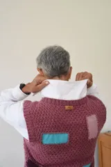 Chaleco tejido a mano en lana merino, con escote en V, cierre frontal de botones de madera y diseño con detalles geométricos de colores.