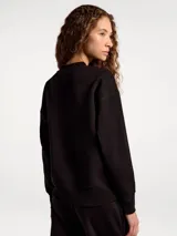 Buzo de cuello redondo en color beige, con diseño liso, mangas largas y puños y ruedo acanalados.