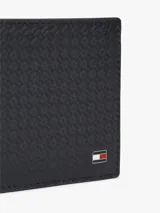 Billetera mini Tommy Hilfiger de cuero azul marino con acabado emboss de monograma TH, diseño compacto con ranuras para tarjetas y placa metálica con el logo de la marca.