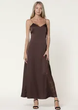 Vestido largo de satén color chocolate, con escote en V y tirantes finos. Presenta un corte fluido con un detalle de godet lateral en encaje a tono.