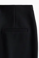 Leggings negros de punto pesado de corte sastre, con elástico oculto en la cintura, bolsillos decorativos en la parte trasera, pliegues cosidos al frente y pequeñas aberturas en los bajos.