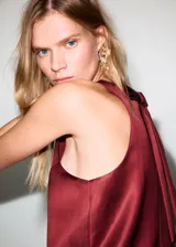 Vestido corto de tejido satinado color bordó, con cuello caja, diseño recto sin mangas y tirantes anchos. Incluye cierre de cremallera en la parte posterior.