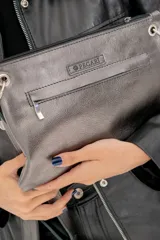 Sobre de cuero vacuno color bordó, con diseño frontal decorado con múltiples remaches metálicos circulares. Cuenta con correa larga ajustable y extraíble, cierre superior y bolsillo trasero con cierre.