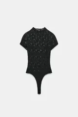 Body de encaje negro con cuello perkins y manga corta. Presenta cierre en la parte inferior con botones a presión.