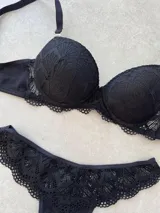 Conjunto de lencería compuesto por un corpiño taza soft con detalles de puntilla y una bombacha tipo less con detalle de encaje en la parte superior.