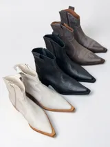 Bota de caÃ±a baja estilo texano confeccionada en cuero 100% genuino en tono marrÃ³n taupe, con taco cuadrado y cierre lateral.