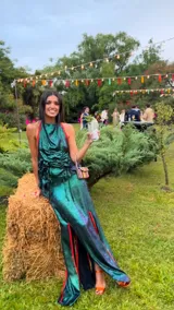 Top de fiesta color verde azulado iridiscente, con escote halter y frunces drapeados en el frente. Presenta un vivo de color naranja rojizo en el borde del escote y tiras para anudar en la espalda.