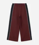 Pantalón de jogging color bordó con paneles laterales en negro y detalles de líneas blancas. Presenta un corte holgado y cintura elástica con cordón de ajuste.