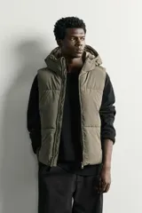 Chaleco acolchado puffer color negro para hombre, de corte regular fit, con capucha ajustable, cierre frontal de cremallera y bolsillos laterales de vivo.