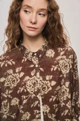 Camisa de silueta amplia y largo por debajo de la cadera, confeccionada en tela liviana con estampado floral en tonos marrón y tostado. Presenta cuello clásico, cierre frontal con botones y mangas tres cuartos.