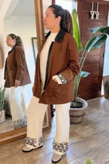 Campera de ecocuero color chocolate, con diseño amplio y relajado. Presenta cuello camisero, cierre frontal con cremallera y botones a presión, además de bolsillos delanteros amplios.
