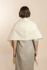 Chal de lana fina sin teñir con diseño de cuadros sutiles, cierre frontal con alamar y bolsillos de cuero metalizado. Presenta terminaciones con flecos en el ruedo y un calce estructurado en los hombros.