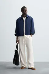 Cazadora bomber azul marino de corte regular fit, confeccionada en tejido de algodón. Presenta cuello solapa, manga larga con puño ajustable de botón, bolsillos de vivo en la cadera, bolsillo interior y bajo con elástico. Cierre frontal con cremallera.