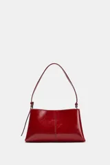 Bolso de hombro en formato mini color rojo, con detalle de pespuntes centrales y asa ajustable. Cuenta con compartimento interior con cremallera y doble compartimento exterior con cierre imantado.