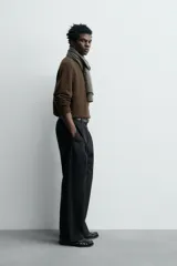 Jersey de punto de lana color marrón oscuro, de calce regular y manga larga, con cuello redondo y acabados enrollados en puños y ruedo.