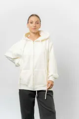Campera deportiva con capucha de corte oversize, confeccionada en tejido suave con interior forrado en piel sintética. Presenta cierre frontal completo, bolsillos laterales y capucha amplia con cordones largos ajustables.