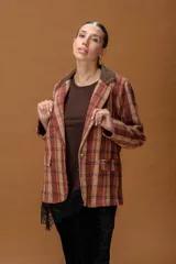 Blazer de tejido con diseño a cuadros en tonos tierra, con solapa de pana en color marrón oscuro, cierre frontal con botón y bolsillos laterales con solapa.