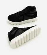Championes de corte medio confeccionados en poliuretano negro, con diseño de paneles combinados y perforaciones laterales. Presentan cierre con cordones y una suela track alta de color blanco con relieve.