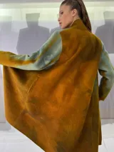 Tapado largo de fieltro de lana merino con teñido artesanal tie-dye en degradé de azul. Tiene cuello alto, cierre lateral con broches ocultos, bolsillos laterales y corte amplio.