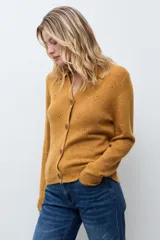 Cardigan de punto color ocre, con diseño calado de pequeños motivos florales, cuello polo y cierre frontal con botones.