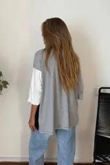 Remerón de manga tres cuartos con diseño de bloques de color en diagonal: gris claro en la parte superior izquierda, negro en la parte inferior derecha y blanco en la manga derecha. Posee cuello redondo y calce holgado.