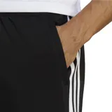 Pantalón de training Adidas negro con tres rayas blancas a los costados, cintura elástica con cordón ajustable y tecnología Aeroready.