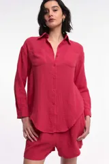 Camisa de manga larga color rojo, con cuello camisero, cierre frontal de botones y dos bolsillos plaque en el pecho.