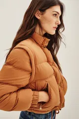 Campera puffer color tostado, con cierre frontal y botones a presión, cuello alto y puños tejidos acanalados.