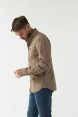 Camisa de hombre color beige con efecto stone wash, corte regular, cuello clásico, cierre frontal con botones, dos bolsillos con solapa abotonada en el pecho y mangas largas con puños abotonados.