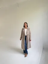 Tapado largo de paño en color beige, con solapas anchas, cierre frontal de un botón y diseño estructurado.