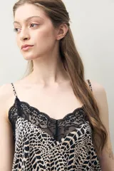Top de pijama de silueta relajada con estampado animal print en tonos beige y negro. Presenta escote en V con encaje floral negro y tiras finas regulables.