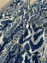 Vestido largo con estampado tribal en tonos azul índigo y blanco. Presenta un escote profundo en V con tirantes tipo halter y cintura elástica ancha que da paso a una falda con vuelo en capas.
