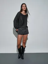 Short de jean blanco con tachas doradas decorativas en los bolsillos delanteros y en los laterales, talle medio y cierre frontal con botón y cremallera.
